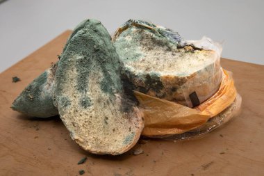 Ahşap bir yüzeyde küflü ekmek dilimi, bozulmuş gıda konsepti.