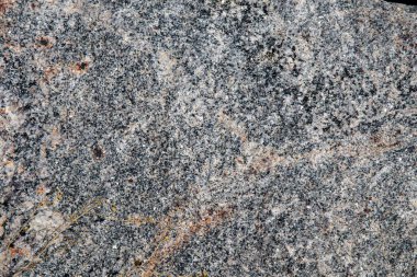 Turuncu mineral damarlı kaba gri granit kaya dokusuna yakın çekim, jeolojik veya soyut arkaplan kullanımı için doğal taş yüzeyi