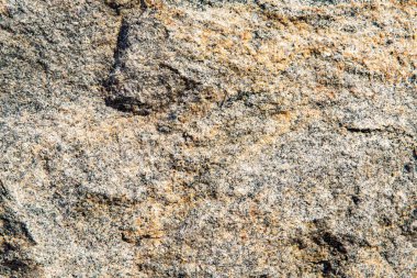 Turuncu mineral damarlı kaba gri granit kaya dokusuna yakın çekim, jeolojik veya soyut arkaplan kullanımı için doğal taş yüzeyi
