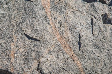 Turuncu mineral damarlı kaba gri granit kaya dokusuna yakın çekim, jeolojik veya soyut arkaplan kullanımı için doğal taş yüzeyi