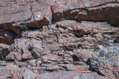 Doğal çatlaklar ve gölgeli pembe granit kaya dokusunun yakın çekimi, tasarım veya doğa temalı projeler için jeolojik arkaplan
