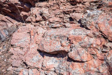Doğal çatlaklar ve gölgeli pembe granit kaya dokusunun yakın çekimi, tasarım veya doğa temalı projeler için jeolojik arkaplan