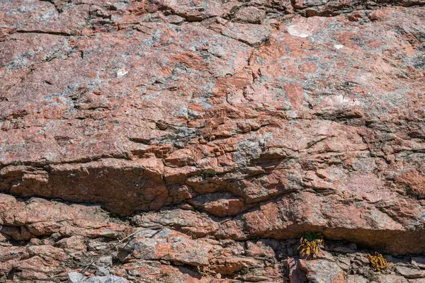 Doğal çatlaklar ve gölgeli pembe granit kaya dokusunun yakın çekimi, tasarım veya doğa temalı projeler için jeolojik arkaplan