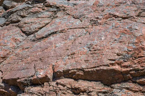 Doğal çatlaklar ve gölgeli pembe granit kaya dokusunun yakın çekimi, tasarım veya doğa temalı projeler için jeolojik arkaplan