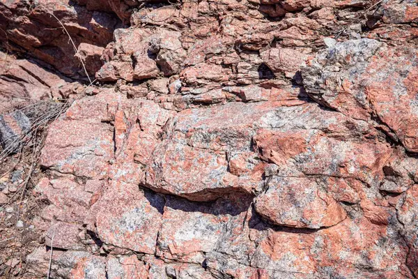 Doğal çatlaklar ve gölgeli pembe granit kaya dokusunun yakın çekimi, tasarım veya doğa temalı projeler için jeolojik arkaplan