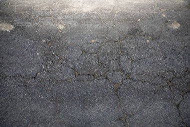 Kırık asfalt yol yüzeyinde geniş çatlaklar, kentsel grunge dokusu arka planı