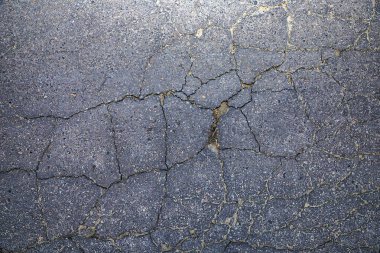 Kırık asfalt yol yüzeyinde geniş çatlaklar, kentsel grunge dokusu arka planı