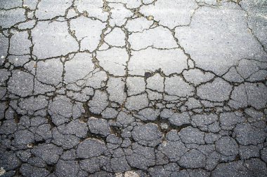 Kırık asfalt yol yüzeyinde geniş çatlaklar, kentsel grunge dokusu arka planı