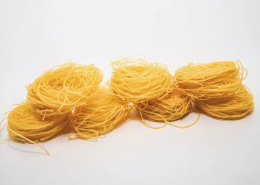 Beyaz arka planda ince spagetti dolu çiğ İtalyan makarna yuvaları.