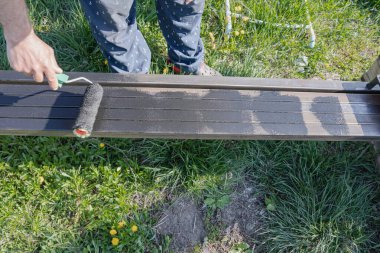 Güneşli bir günde, dışarıda paten fırçasıyla metal bir yapı boyamak, boyama sürecinin ve işçilerin ellerinin yakın çekimi.