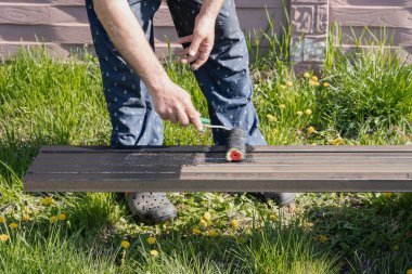 Güneşli bir günde, dışarıda paten fırçasıyla metal bir yapı boyamak, boyama sürecinin ve işçilerin ellerinin yakın çekimi.