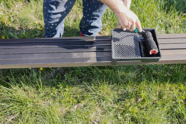 Güneşli bir günde, dışarıda paten fırçasıyla metal bir yapı boyamak, boyama sürecinin ve işçilerin ellerinin yakın çekimi.