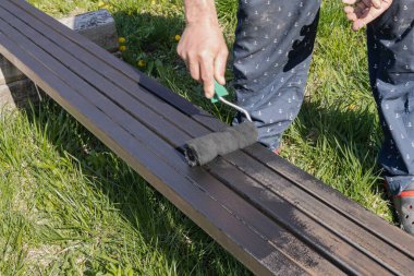 Güneşli bir günde, dışarıda paten fırçasıyla metal bir yapı boyamak, boyama sürecinin ve işçilerin ellerinin yakın çekimi.