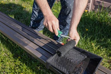 Güneşli bir günde, dışarıda paten fırçasıyla metal bir yapı boyamak, boyama sürecinin ve işçilerin ellerinin yakın çekimi.