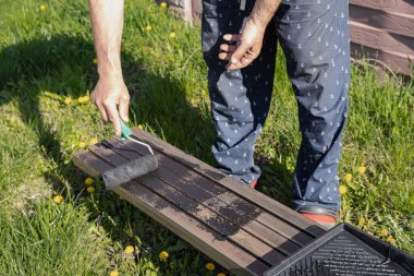 Güneşli bir günde, dışarıda paten fırçasıyla metal bir yapı boyamak, boyama sürecinin ve işçilerin ellerinin yakın çekimi.
