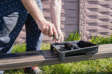 Güneşli bir günde, dışarıda paten fırçasıyla metal bir yapı boyamak, boyama sürecinin ve işçilerin ellerinin yakın çekimi.