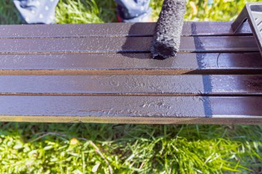 Güneşli bir günde, dışarıda paten fırçasıyla metal bir yapı boyamak, boyama sürecinin ve işçilerin ellerinin yakın çekimi.