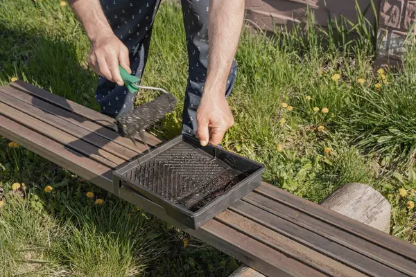 Güneşli bir günde, dışarıda paten fırçasıyla metal bir yapı boyamak, boyama sürecinin ve işçilerin ellerinin yakın çekimi.