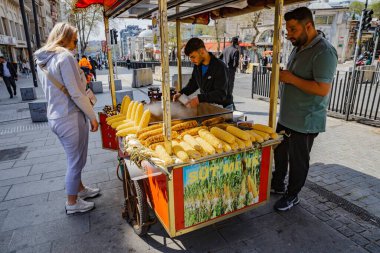 İstanbul, Türkiye 'de 6 Nisan 2025' te mısır ve kavrulmuş kestane satan sokak yemekleri satıcısı