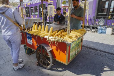 İstanbul, Türkiye 'de 6 Nisan 2025' te mısır ve kavrulmuş kestane satan sokak yemekleri satıcısı