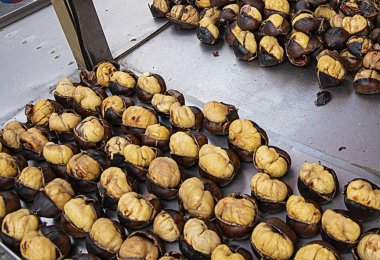 Metal sokak yemek arabasında kavrulmuş kestaneler, şehir pazarında geleneksel mevsimlik atıştırmalıklar.