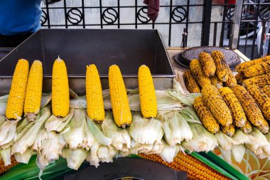 Sokağın yiyecek arabasında ızgara ve taze mısır, şehir ortamında geleneksel yaz atıştırması.