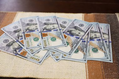 Koyu ahşap bir yüzeye 100 dolarlık banknotlar serpiştirin.