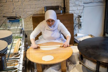 İstanbul Restoranı 'nda Geleneksel Türk Kadını Düz Ekmek Hazırlıyor. Otantik Mutfak Süreci ve Türk Kültürü. 10 Nisan 2025. Sadece Düzenleyici Kullan.