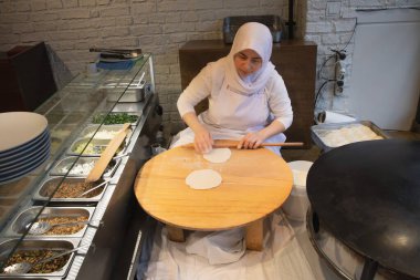 İstanbul Restoranı 'nda Geleneksel Türk Kadını Düz Ekmek Hazırlıyor. Otantik Mutfak Süreci ve Türk Kültürü. 10 Nisan 2025. Sadece Düzenleyici Kullan.