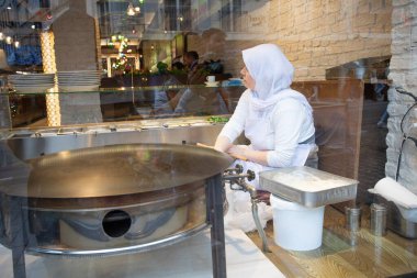 İstanbul Restoranı 'nda Geleneksel Türk Kadını Düz Ekmek Hazırlıyor. Otantik Mutfak Süreci ve Türk Kültürü. 10 Nisan 2025. Sadece Düzenleyici Kullan.