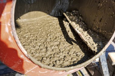 Turuncu beton karıştırıcının içinde kuru çimento ve çakıl var. İnşaat materyali hazırlama.