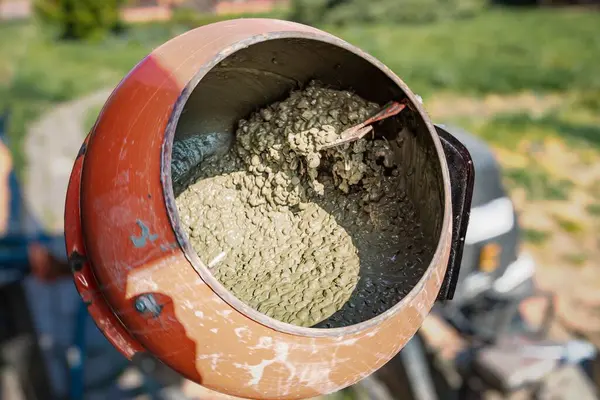 Turuncu beton karıştırıcının içinde kuru çimento ve çakıl var. İnşaat materyali hazırlama.