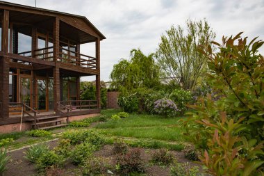 Ağaçlı kır evi ve doğal çevrede yeşil çalılıklar, satılık emlak.