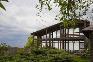 Eko ahşap ev, büyük cam pencereler ve kırsal alanda bahar leylak çalıları.