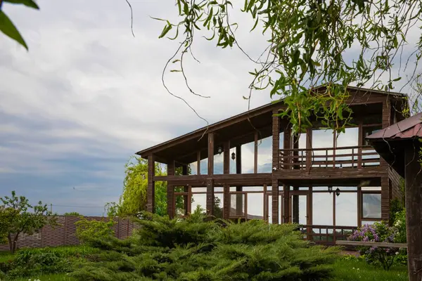 Eko ahşap ev, büyük cam pencereler ve kırsal alanda bahar leylak çalıları.