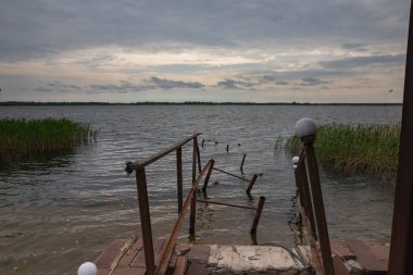 Fırtına, yıkım ve doğal afet kavramı, göldeki kırık ahşap iskele.