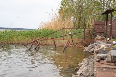Fırtına, yıkım ve doğal afet kavramı, göldeki kırık ahşap iskele.