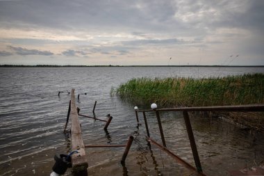 Fırtına, yıkım ve doğal afet kavramı, göldeki kırık ahşap iskele.