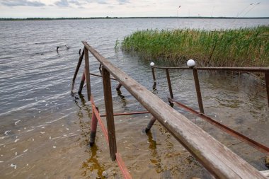 Fırtına, yıkım ve doğal afet kavramı, göldeki kırık ahşap iskele.