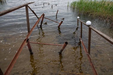 Fırtına, yıkım ve doğal afet kavramı, göldeki kırık ahşap iskele.