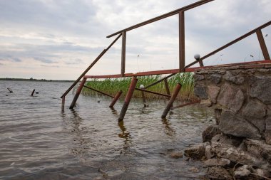 Fırtına, yıkım ve doğal afet kavramı, göldeki kırık ahşap iskele.