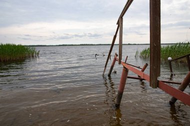 Fırtına, yıkım ve doğal afet kavramı, göldeki kırık ahşap iskele.