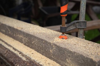 Açık havada tahta kiriş kesen bir adam. Klempler ve elektrikli aletlerle marangozluk işlemi. Ahşap işçiliği, işçiliği, ev yenilemesi ve DIY inşaatı kavramı.