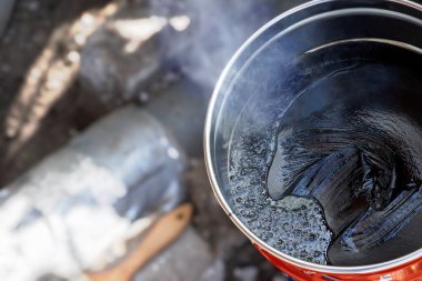 Metal bir tencerede dumanlı katran ya da reçine pişirmek