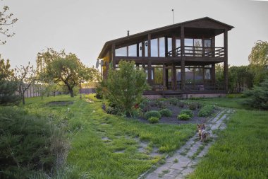 Kırsal kesimde günbatımında bahçeli ahşap bir ev.