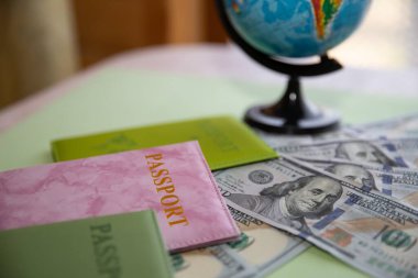 Dolar banknotları, renkli pasaportlar ve küreyle seyahat kavramı