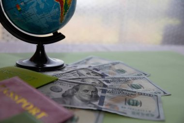 Dolar banknotları, renkli pasaportlar ve küreyle seyahat kavramı