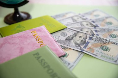 Dolar banknotları, renkli pasaportlar ve küreyle seyahat kavramı