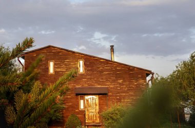 Kırsal kesimde günbatımında bahçeli ahşap bir ev.