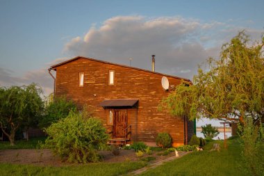 Kırsal kesimde günbatımında bahçeli ahşap bir ev.